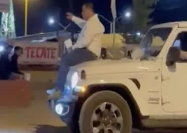 Alcalde pasea en el cofre de camioneta, con una bebida en la mano