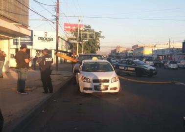 Cae poste de alumbrado sobre taxi