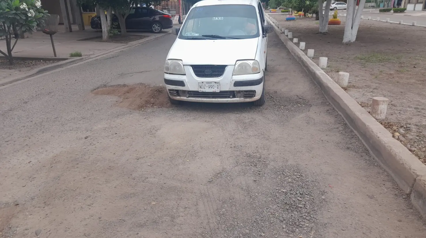 Taxistas colectivos tapan baches con tierra en calle Madero