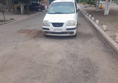 Taxistas colectivos tapan baches con tierra en calle Madero
